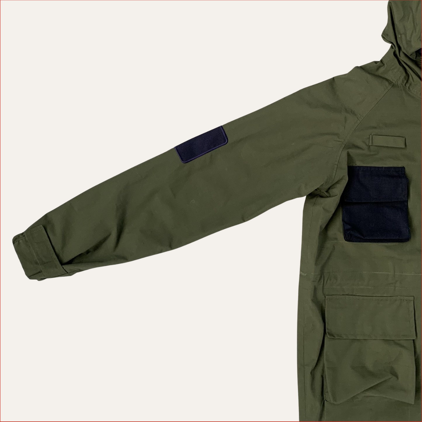 Flat lay photo of a Green Parka jacket by Shoreditch and Hale with navy patches on a white background