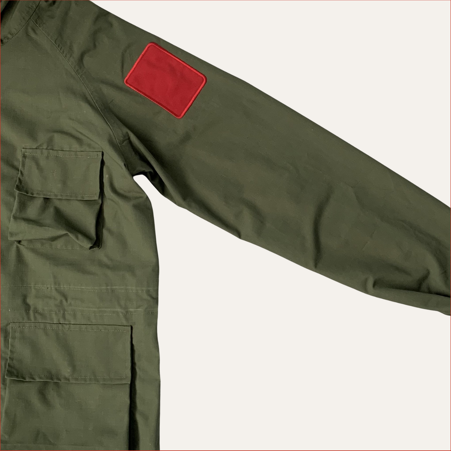 Flat lay photo of a Green Parka jacket by Shoreditch and Hale with red sleeve patches on a white background