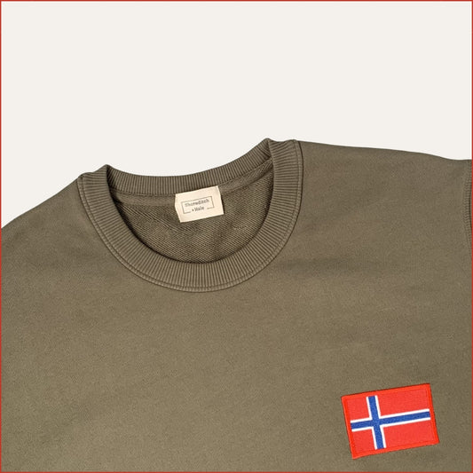 Close up Flay lay image of a shoreditch and hale Green sweatshirt with a small flag patch on a white background. casual menswear