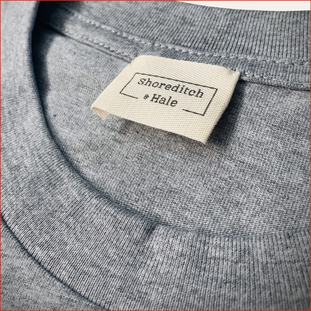Close-up of a gray tshirt with a 'Shoreditch & Hale' twill label. minimalist and understated design by shoreditch and hale