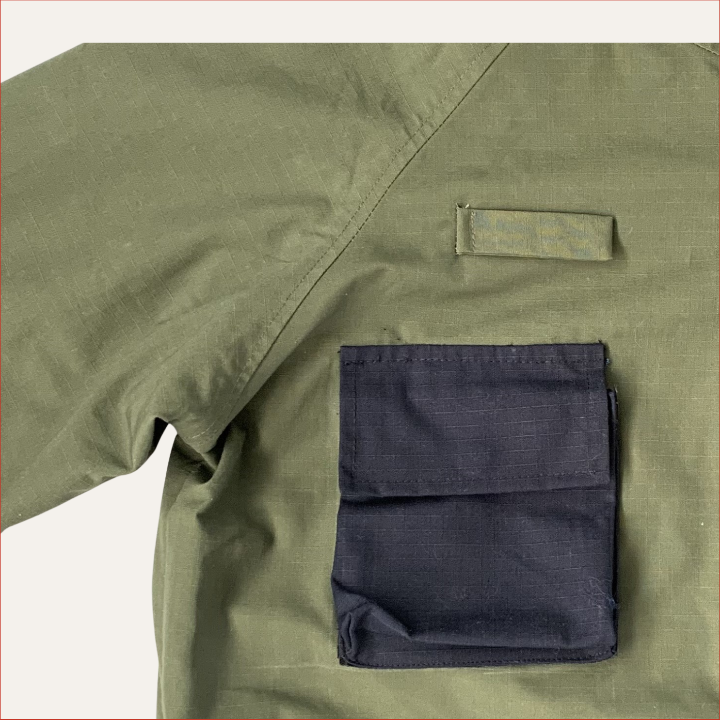 Flat lay photo of a Green Parka jacket by Shoreditch and Hale with navy chest patches on a white background