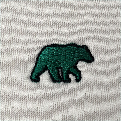 Embroidered green bear design on a light gray fabric background