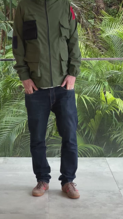 Model wearing a mid length green khaki parka jacket with a blue pocket by shoreditch and hale. minimalist casual menswear
