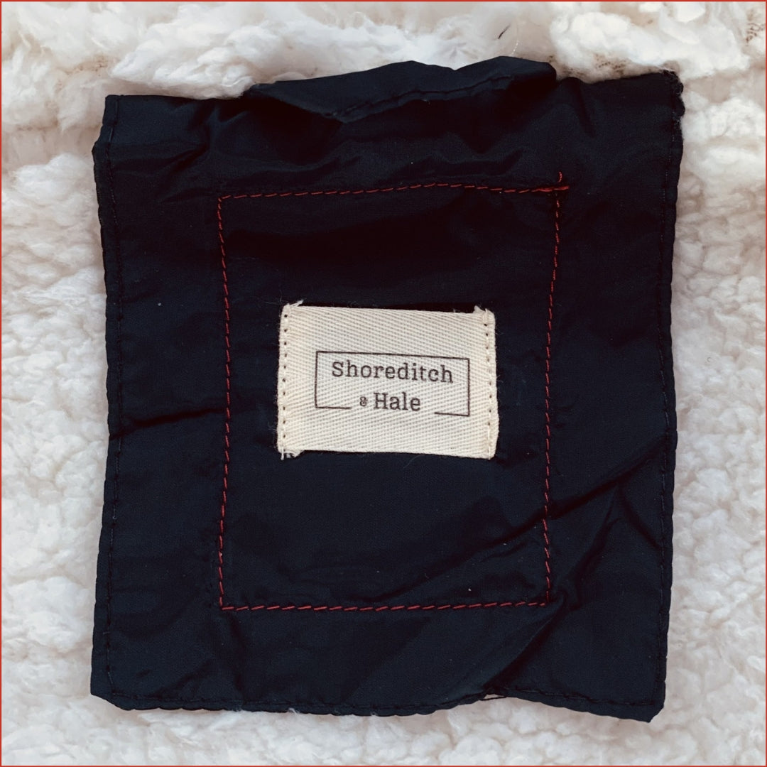Snow white inner fleece of a navy parka with a 'Shoreditch & Hale' twill label.