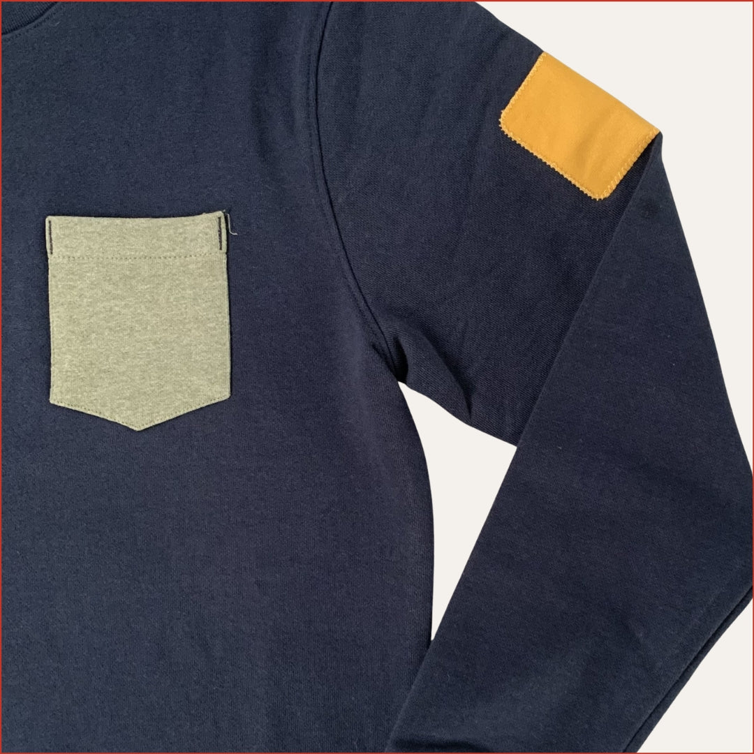 close up image of a men's Navy blue long-sleeve shirt with a green pocket and yellow sleeve patch on a white background. menswear by shoreditch and hale