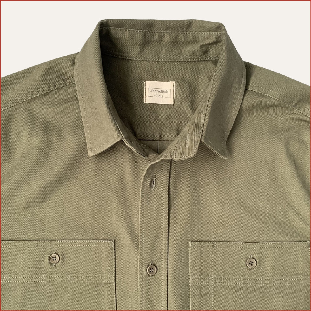 close up image of a khaki cotton drill shirt with two front pockets on a white background. minimalist and understated design casual menswear shoreditch and hale