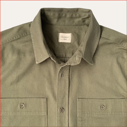 close up image of a khaki cotton drill shirt with two front pockets on a white background. minimalist and understated design casual menswear shoreditch and hale