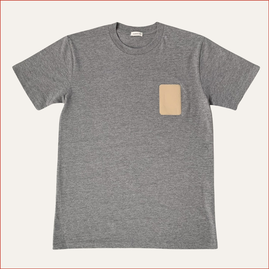 Flay lay photo of a Gray t-shirt with a beige patch on a white background minimalist and understated design by shoreditch and hale