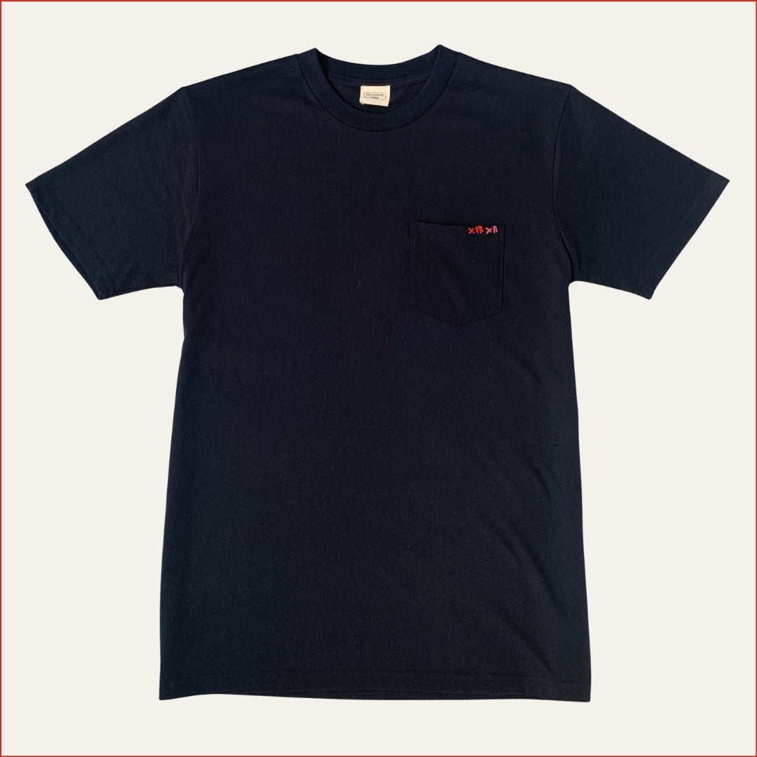 Flat lay image of a men's soft cotton navy pocket tshirt with contrast red stitching on the chest against a white background. Minimalist and understated design by shoreditch and hale.